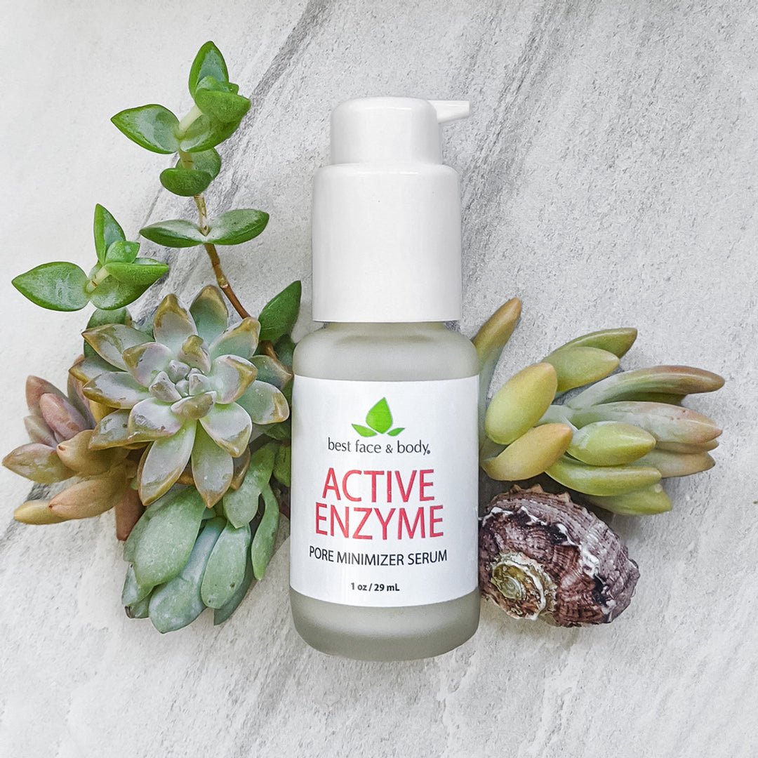 Active Enzyme Pore Minimizer Serum 1 oz frosted glass bottle with white pump top, photographed on a grey stone background with succulents