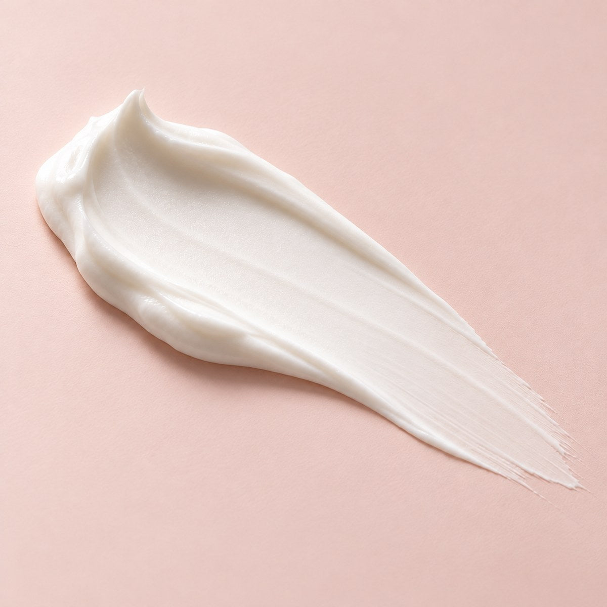 Swipe of rich white creme on a soft pink background