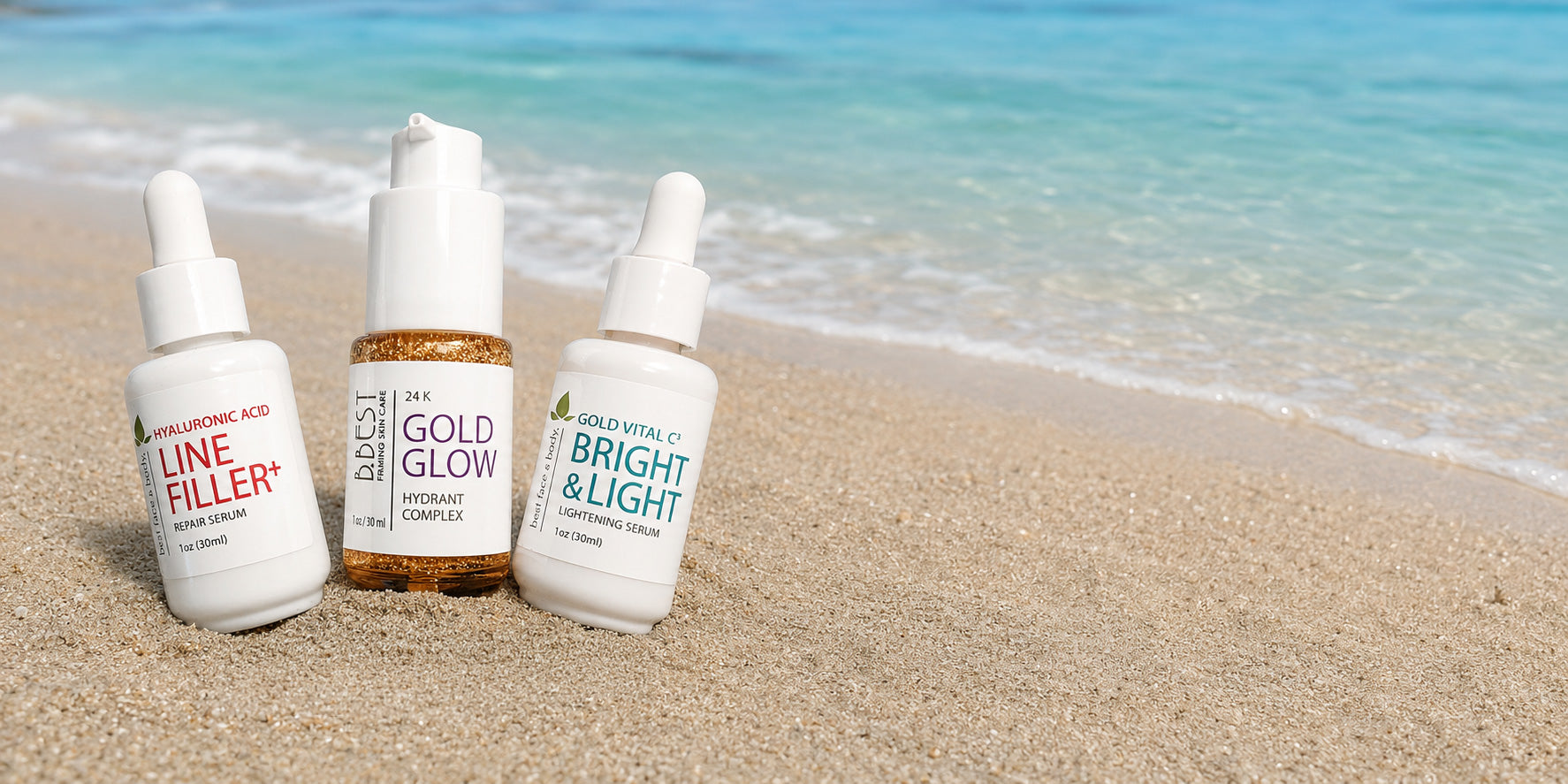 Three skincare serums from best face & body lined up on a sandy beach with turquoise ocean water in the background.
